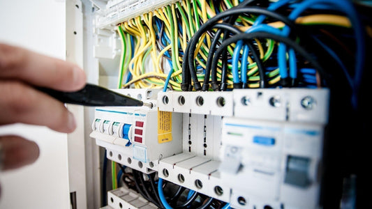 Technician tightening wiring terminals in an industrial control cabinet, representing reliable physical layer connections for automation systems.