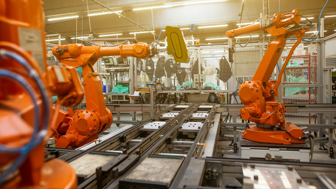 Robotic arms and conveyor belt in a modern automated factory, illustrating the high-speed motion control and synchronization managed by Omron Sysmac NJ and NX series PLCs.