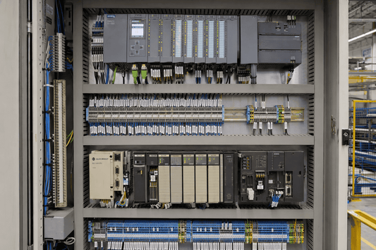 Open mixed-generation industrial control cabinet with modern power hardware and legacy PLCs for industrial system retrofitting