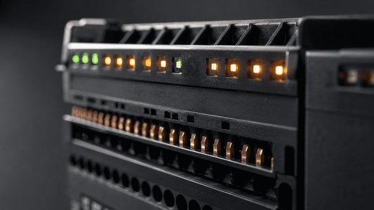 Macro shot of an industrial PLC output module with glowing amber and green diagnostic LED lights and copper contact pins.
